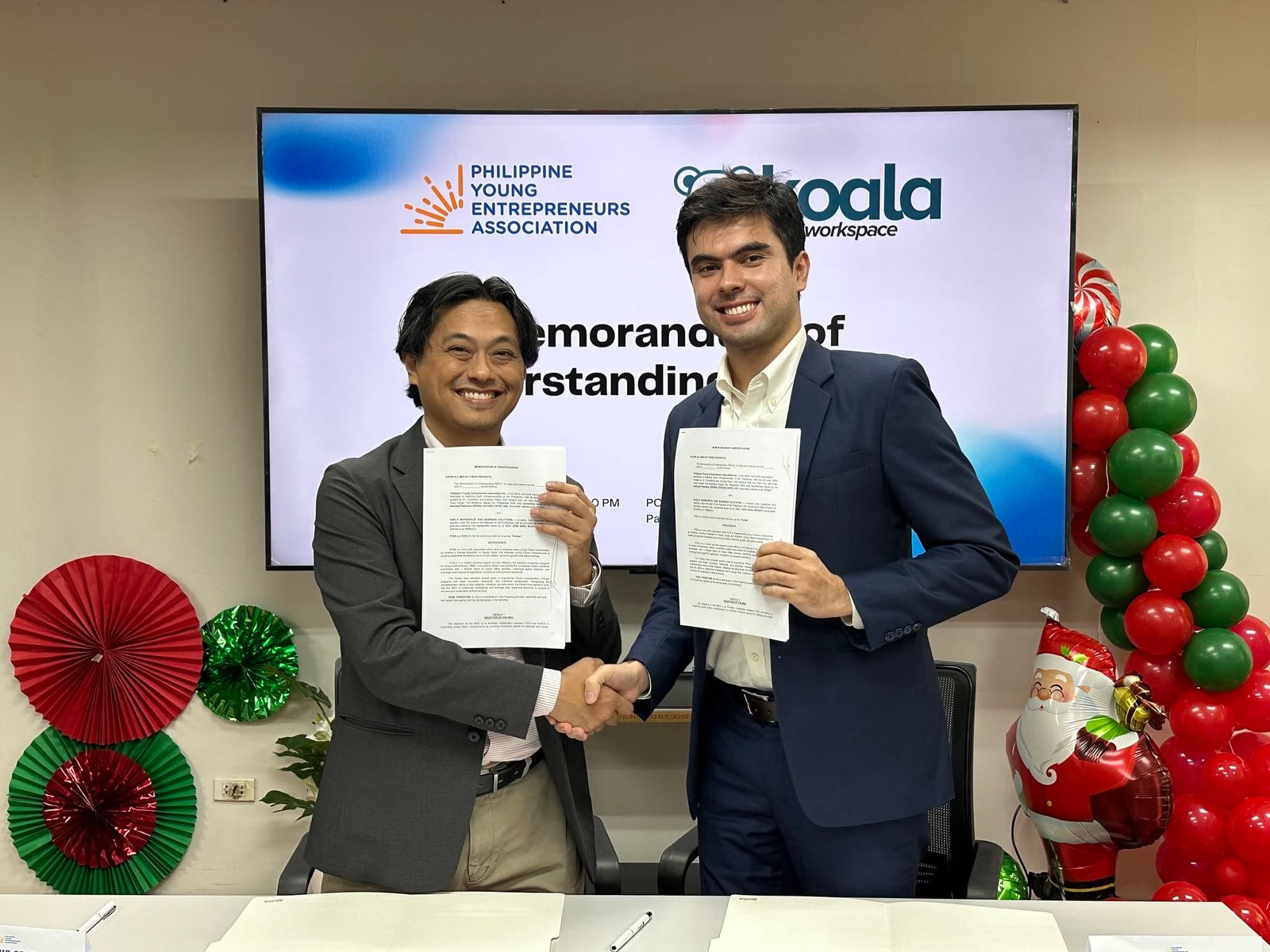 Koala Workspace and PYEA representatives holding the signed partnership agreement